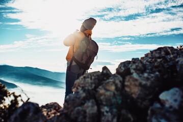 Cheering woman backpacker enjoy the view on sunrise mountain top cliff edge