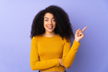 Young african american woman isolated on purple background happy and pointing up