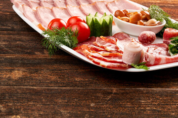A plate of deli meats, garnished with cherry tomatoes, mushrooms and herbs, parsley. Copy space