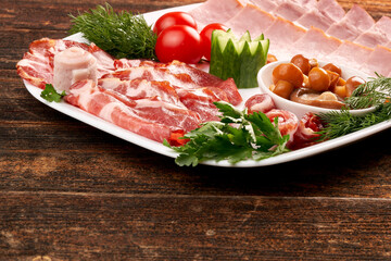 A plate of deli meats, garnished with cherry tomatoes, mushrooms and herbs, parsley. Copy space