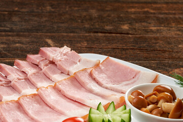 Ham on a plate, still life on a wooden natural background.