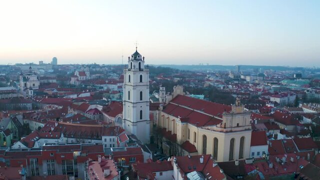 Church of St. Johns in old town Vilnius on beautiful day. Aerial flyby wide shot.