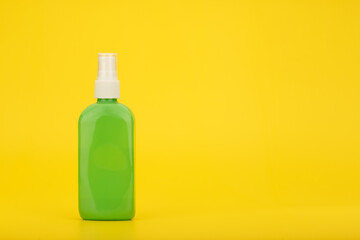 Sunscreen spray against yellow background with copy space. Sunscreen product for tanning in green plastic tube. Minimalistic template for summer skin care concept