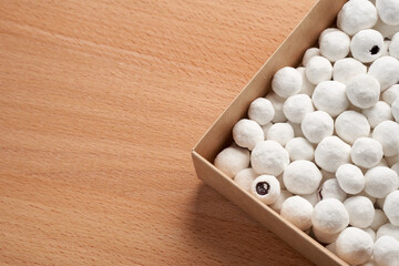 Cranberries in powdered sugar in a cardboard box on a wooden background. Sweets in the winter with copy space. Close-up.