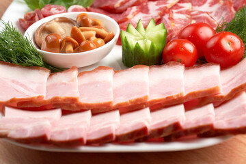 Sliced ham and Italian coppa on a white platter, garnish with cucumber and herbs. Festive table setting in a cafe for the anniversary. Close-up.