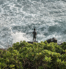 Rybak, wędkarz podczas łowienia ryb, na tle oceanu i wybrzeża. © insomniafoto