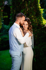 Happy and beautiful bride and groom gently cuddle in the park