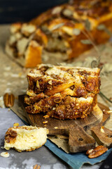 Homemade braided cake Babka with pecan nuts and cinnamon on craft paper. Easter sweet pastry. 