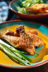 Fried chicken legs with green onions and spices on the table in a beautiful arrangement