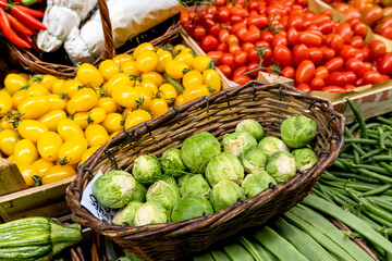 Broccoli, zucchini, green beans, brussels sprouts and red tomatoes in baskets at local farmer's market . Healthy food eating organic vegetables. selective focus