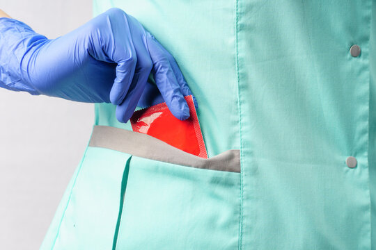 female doctor in medical gloves pulls a condom out of her pocket.