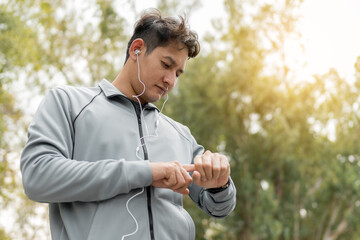 Male runner using smart watch to monitor performance. Sport man is setting up his smart watch before running in the morning