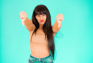 Fototapeta premium Young woman over isolated green background showing thumbs down.