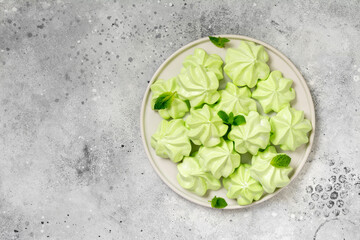 Mint or fruit meringue in a white plate on a light gray kitchen table. French or Italian protein dessert