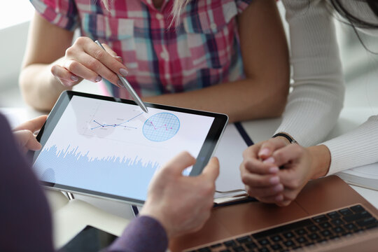 Group of people discussing graph on digital tablet closeup. Profit growth concept