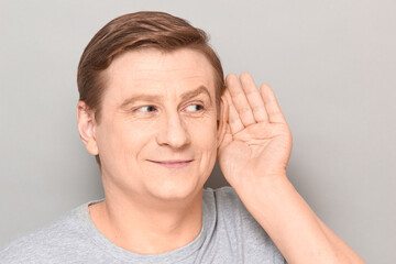 Portrait of happy man placing hand near ear and eavesdropping