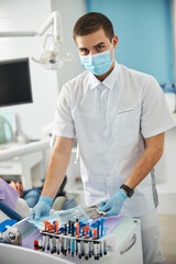 Man in white scrubs getting dental tools from plastic bag