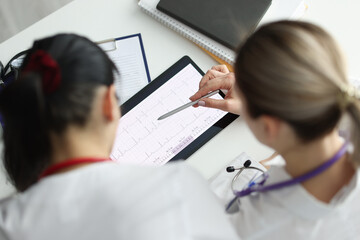 Doctors studying electrocardiogram on digital tablet closeup. Medical education concept