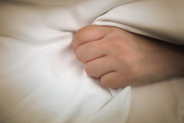 Female patient gripping a fistfull of the bed sheets in one hand