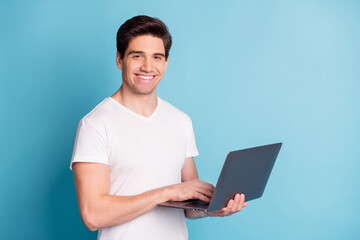 Photo of handsome satisfied young person hand hold netbook look camera isolate don blue color...