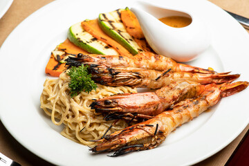 Grilled King prawns or shrimps with noodles and grilled veggies and sauce.