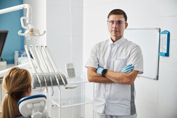 Dental surgeon standing with crossed arms in his office