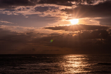 Zachód słońca nad oceanem i skalistym wybrzeżem.