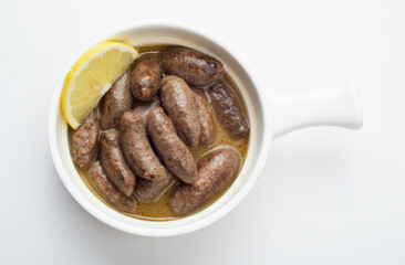 Lebanese starters of Makanek meat marinated, sausages fried in a metal pan isolated on white.