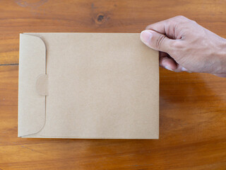 A hand holding a paper envelope