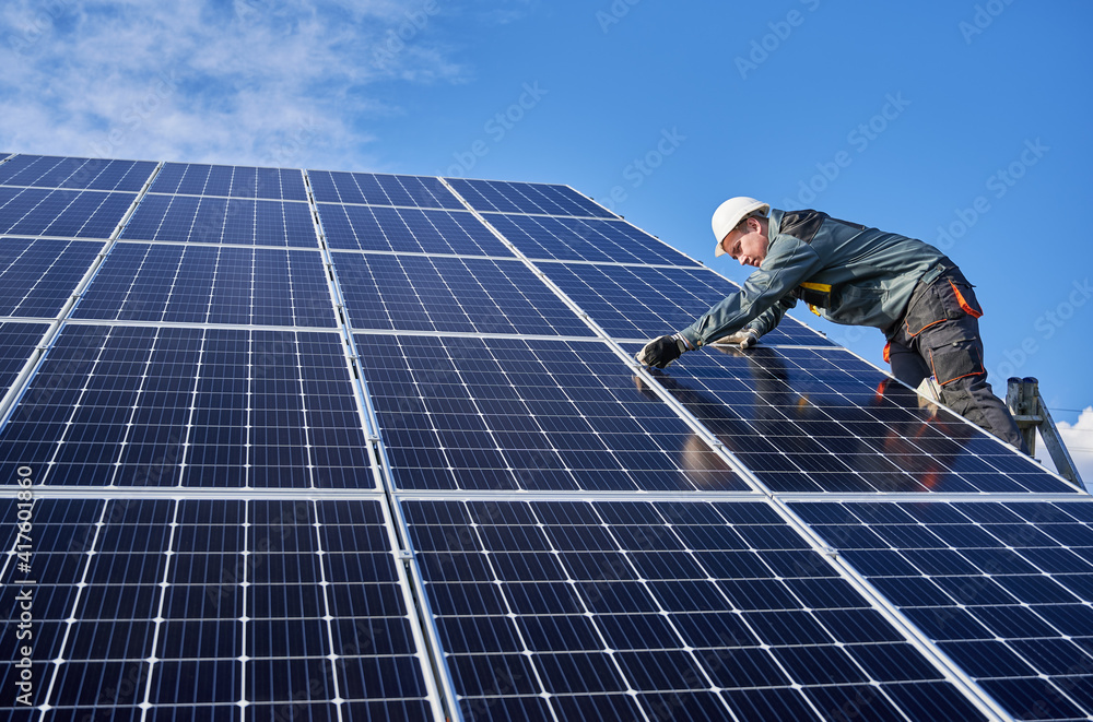 Wall mural horizontal snapshot of beautiful and shiny solar battery surface and male worker wearing a uniform, 