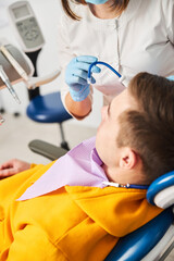 Person folding a dental saliva ejector near male client face