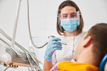 Dental surgeon standing over patient with teeth polishing handpiece