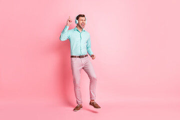 Full size photo of young happy crazy excited cheerful man dancing listen music in headphones isolated on pink color background