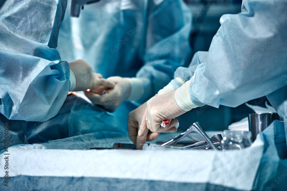 Poster hands of a team of surgeons close-up in the operating room during the operation, sterile instruments