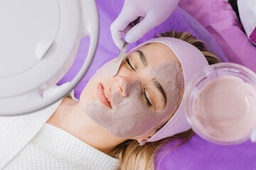 A beautician applying mask to the client in the beauty salon