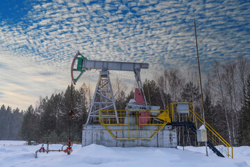 Oil pumpjack winter working. Oil rig energy industrial machine for petroleum in the sunset background for design.