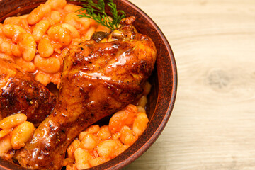Ready-made, baked chicken legs in spices with beans. Boiled beans and chicken legs are served hot in a bowl. The concept of a hearty meal.