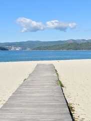 Beach with wooden boardwalk and blue sky at Rias Baixas region. Porto do Son, Coruña, Galicia, Spain.
