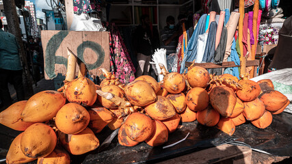 Pomarańczowe owoce kokosowe na stoisku na bazarze. - obrazy, fototapety, plakaty
