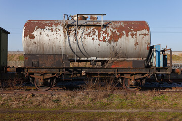 Fototapeta na wymiar Old train cistern tank wagon, rusty and weathered on abandoned train tracks in the field