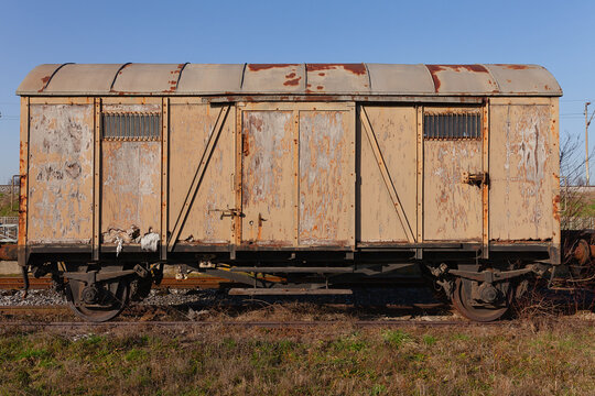 Old rusty brown train wagon on abandoned tracks in the field