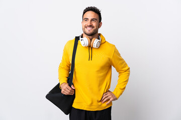 Young sport man with sport bag isolated on white background posing with arms at hip and smiling