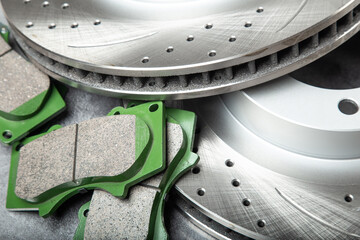 brake pads and perforated brake discs on a stone gray table