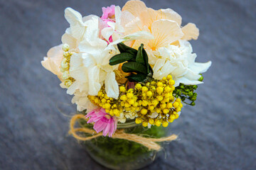 small delicate flower arrangement of preserved flowers in glass pot