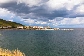 Panorama view of the beautiful fishing village of Erbalunga with dramatic sky, in Cap Corse, Corsica, France. Tourism and vacations concept.