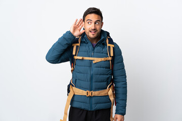 Young mountaineer man with a big backpack isolated on white background listening something