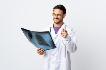 Young doctor man holding a radiography isolated on white background points finger at you