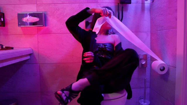 sexy lady is playing with toilet paper in restroom in hotel, drunk bdsm prostitute is waiting client