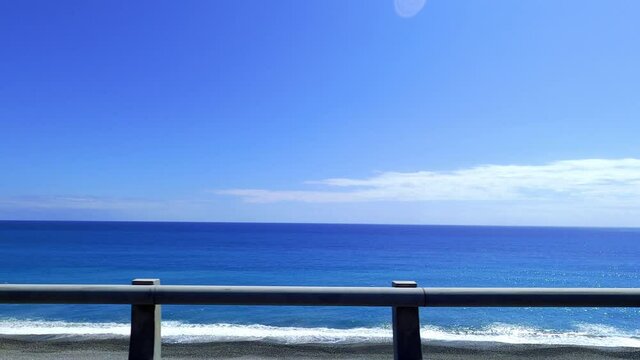 
POV-Passenger side window driving scene. blue ocean against  blue sky