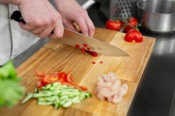 Chef man cutting chili peppers at table, closeup